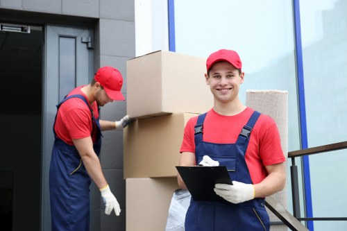 Movers carrying boxes through a Chelsea townhouse entrance